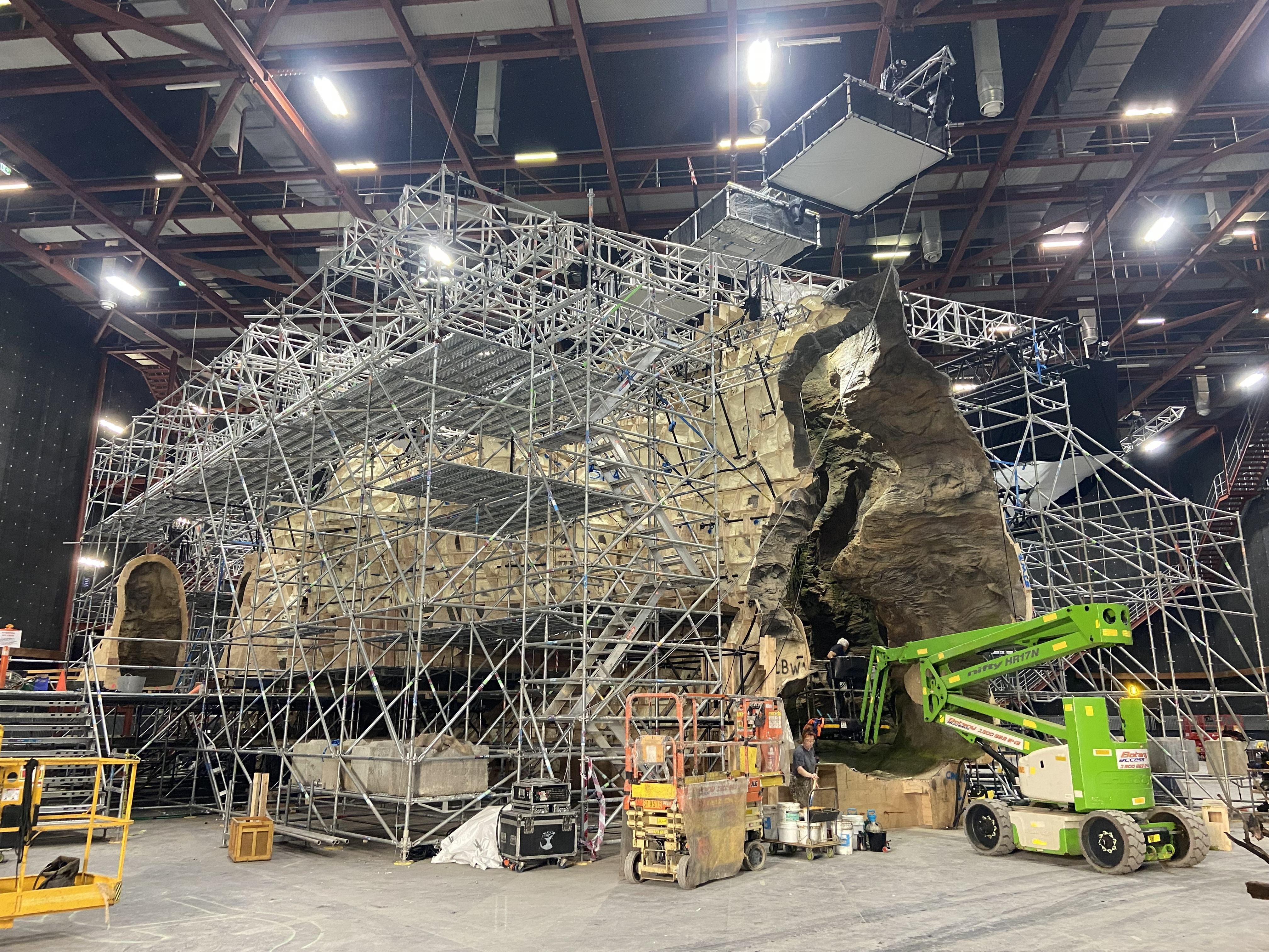 Wide elevated view showing the complete scaffold structure, cave geometry and construction machinery.